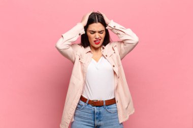 Genç ve güzel bir kadın stresli ve hayal kırıklığına uğramış hissediyor, elele tutuşuyor, yorgun, mutsuz ve migren ağrısı çekiyor.