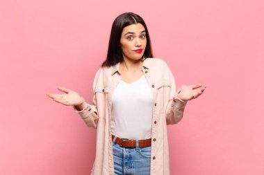 Genç ve güzel bir kadın şaşkın ve şaşkın hissediyor, doğru cevap ya da karardan emin değil, bir seçim yapmaya çalışıyor.