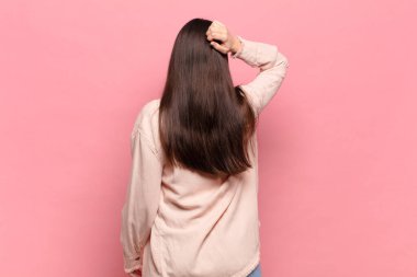 Genç, güzel bir kadın bilgisiz ve kafası karışık hissediyor, bir çözüm düşünüyor, eli kalçasında, diğeri kafasında, dikiz aynasından.