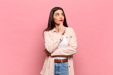 Genç, güzel bir kadın düşünceli, meraklı ya da hayal kuruyor, hayal kuruyor ve gökyüzüne bakıyor.