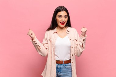 Genç, güzel bir kadın mutlu, pozitif ve başarılı hissediyor, zaferi, başarıları ya da iyi şansı kutluyor.