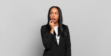 young black woman with surprised, nervous, worried or frightened look, looking to the side towards copy space. business concept