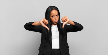 young black woman looking sad, disappointed or angry, showing thumbs down in disagreement, feeling frustrated. business concept