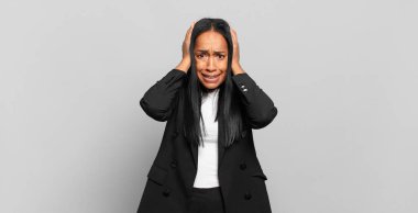 young black woman feeling stressed, worried, anxious or scared, with hands on head, panicking at mistake. business concept