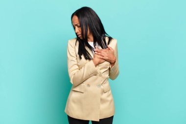 young black woman looking sad, hurt and heartbroken, holding both hands close to heart, crying and feeling depressed. business concept