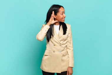 young black woman smiling, looking curiously to the side, trying to listen to gossip or overhearing a secret. business concept