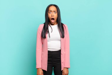 young black woman feeling terrified and shocked, with mouth wide open in surprise. business concept