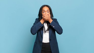 young black woman covering mouth with hands with a shocked, surprised expression, keeping a secret or saying oops. business concept