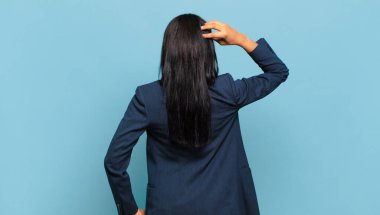 young black woman feeling clueless and confused, thinking a solution, with hand on hip and other on head, rear view. business concept