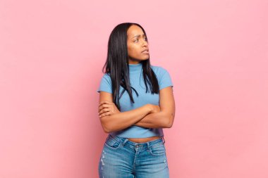 young black woman doubting or thinking, biting lip and feeling insecure and nervous, looking to copy space on the side