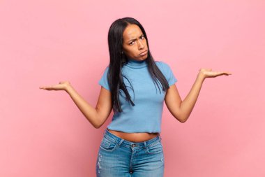 young black woman looking puzzled, confused and stressed, wondering between different options, feeling uncertain
