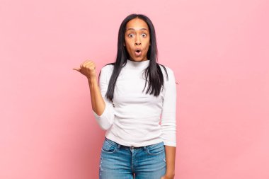 Genç siyahi kadın inançsızlıktan şaşkın şaşkın bakıyor, yan taraftaki objeyi işaret ediyor ve diyor ki: