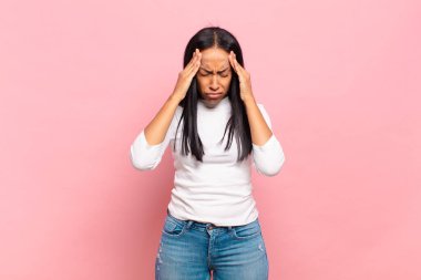 Genç siyahi kadın stresli ve hayal kırıklığına uğramış görünüyor. Baskı altında, baş ağrısı ve sorunlarla çalışıyor.