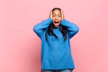 Genç siyahi kadın el ele tutuşuyor, ağzı açık, son derece şanslı, şaşırmış, heyecanlı ve mutlu hissediyor.