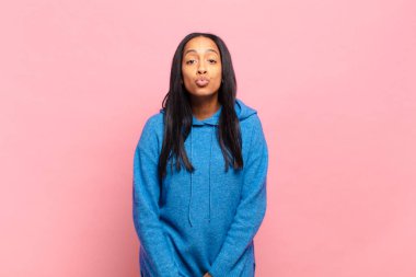 young black woman pressing lips together with a cute, fun, happy, lovely expression, sending a kiss