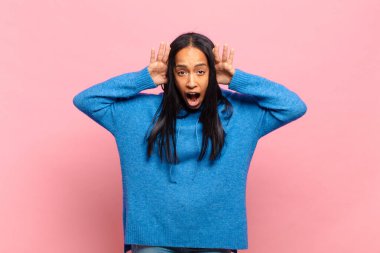 Genç siyahi kadın panik ya da öfke içinde bağırıyor, şok olmuş, korkmuş ya da öfkeli, elleri başının yanında.