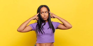 young black woman feeling confused or doubting, concentrating on an idea, thinking hard, looking to copy space on side