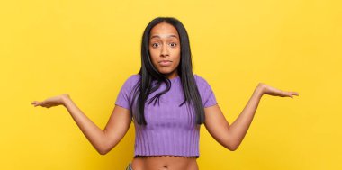 young black woman feeling puzzled and confused, doubting, weighting or choosing different options with funny expression