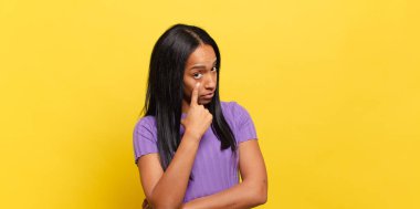 young black woman keeping an eye on you, not trusting, watching and staying alert and vigilant