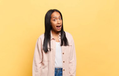 Genç siyah bir kadın, büyük, dostane, kaygısız bir gülümsemesi var, pozitif, rahat ve mutlu görünüyor, ürpertici.