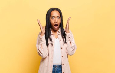 Genç siyahi kadın şok olmuş ve hayrete düşmüş görünüyor. İnanılmaz bir şey fark ettiğinde ağzı açık kalıyor.