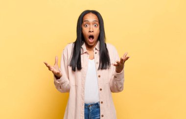 Genç siyahi kadın ağzı açık ve şaşırmış, şok olmuş ve hayrete düşmüş inanılmaz bir sürprizle
