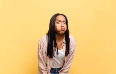 Aptal, çılgın, şaşkın bir ifadeyle genç siyahi kadın, yanakları şişmiş, doldurulmuş, şişman ve yemekle dolu.