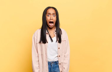 Genç siyahi kadın korkmuş ve şok olmuş hissediyor, ağzı açık şaşkınlık içinde.