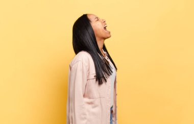 Genç siyah kadın öfkeyle bağırıyor, agresif bir şekilde bağırıyor, stresli ve kızgın görünüyor.