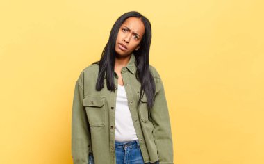 young black woman feeling puzzled and confused, with a dumb, stunned expression looking at something unexpected