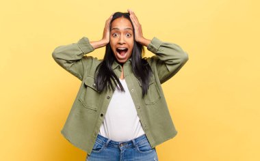 Genç siyahi kadın el ele tutuşuyor, ağzı açık, son derece şanslı, şaşırmış, heyecanlı ve mutlu hissediyor.