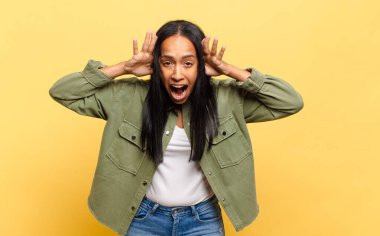 Genç siyahi kadın panik ya da öfke içinde bağırıyor, şok olmuş, korkmuş ya da öfkeli, elleri başının yanında.