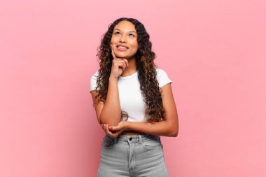 Genç İspanyol kadın mutlu bir şekilde gülümsüyor ve hayal kuruyor ya da şüphe ediyor.