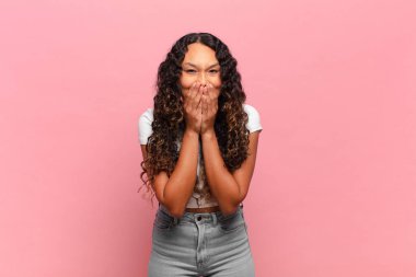 Genç İspanyol kadın mutlu, neşeli, şanslı ve şaşkın görünüyor. İki eliyle ağzını kapatıyor.