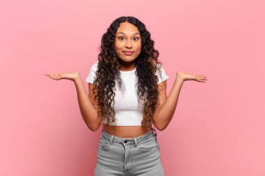 Genç İspanyol kadın şaşkın ve kafası karışık, şüpheci, farklı seçenekleri tartıyor veya komik bir ifadeyle seçiyor.