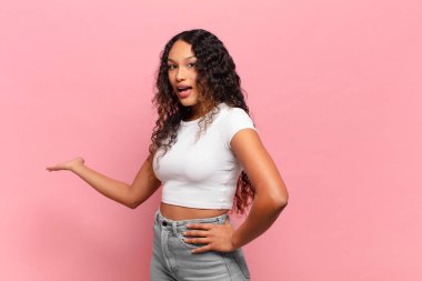 Genç İspanyol kadın kendini mutlu ve neşeli hissediyor, gülümsüyor ve seni hoş karşılıyor, seni dostça bir jestle içeri davet ediyor.