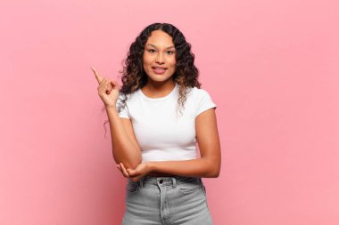 Genç İspanyol kadın mutlu bir şekilde gülümsüyor ve yan bakıyor, merak ediyor, düşünüyor ya da bir fikri var.