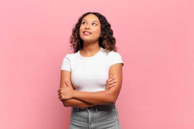 Genç İspanyol kadın mutlu, gururlu ve umutlu hissediyor, merak ediyor ya da düşünüyor, çapraz kollarla fotokopi çekmeyi bekliyor.