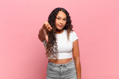 Genç İspanyol kadın kızgın, sinirli, hayal kırıklığına uğramış ya da canı sıkkın, ciddi bir bakışla başparmağını kaldırıyor.