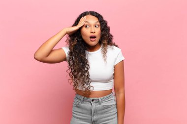 Genç İspanyol kadın mutlu, şaşkın ve şaşırmış görünüyor, gülümsüyor ve inanılmaz ve inanılmaz iyi haberleri fark ediyor.