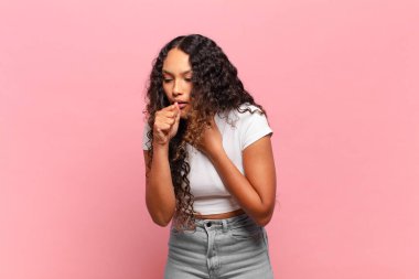 Boğazı ağrıyan ve grip belirtileri gösteren ağzı kapalı öksüren genç İspanyol kadın.