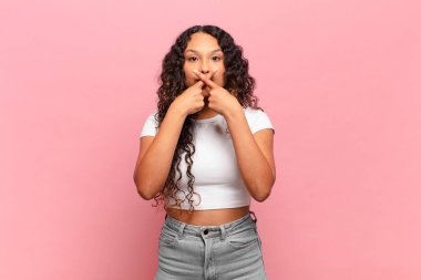 Latin kökenli genç bir kadın ciddi görünüyor ve iki parmağının önde olması hoşnutsuzca karşılıyor. Sessizlik istiyor.