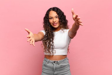 Genç İspanyol kadın neşeyle gülümsüyor sıcak, dostça, sevgi dolu bir kucak veriyor, mutlu ve sevimli hissediyor.