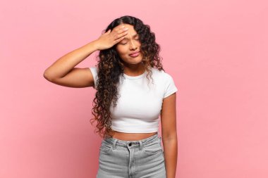 Genç İspanyol kadın stresli, yorgun ve hayal kırıklığına uğramış görünüyor, alnından ter damlıyor, umutsuz ve bitkin hissediyor.