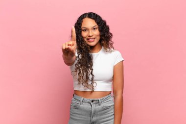 Genç İspanyol kadın gülümsüyor ve arkadaş canlısı görünüyor, bir numara veya ilk eli önde, geriye doğru sayıyor.