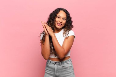 Genç İspanyol kadın mutlu ve başarılı hissediyor, gülümsüyor ve alkışlıyor, alkışlarla tebrik ediyor.