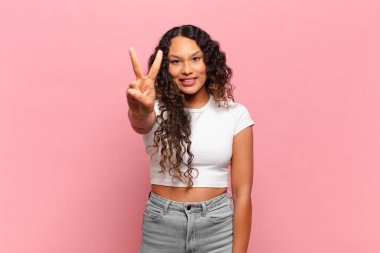 Genç İspanyol kadın gülümsüyor ve arkadaş canlısı görünüyor. İki ya da iki numarayı gösteriyor. Elleri önde, geri sayıyor.