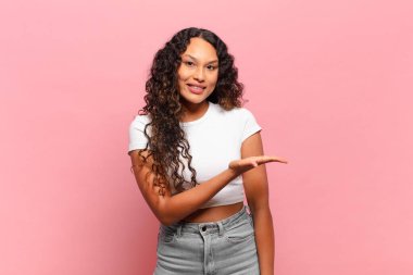 Genç İspanyol kadın neşeyle gülümsüyor, mutlu hissediyor ve fotokopi uzayda bir konsept gösteriyor.