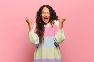 Genç İspanyol kadın son derece mutlu ve şaşırmış görünüyor, başarıyı kutluyor, bağırıyor ve zıplıyor.