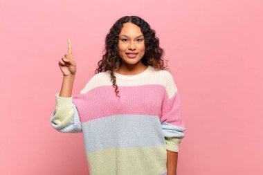 Genç İspanyol kadın mutlu bir şekilde gülümsüyor, tek eliyle uzayı işaret ediyor.